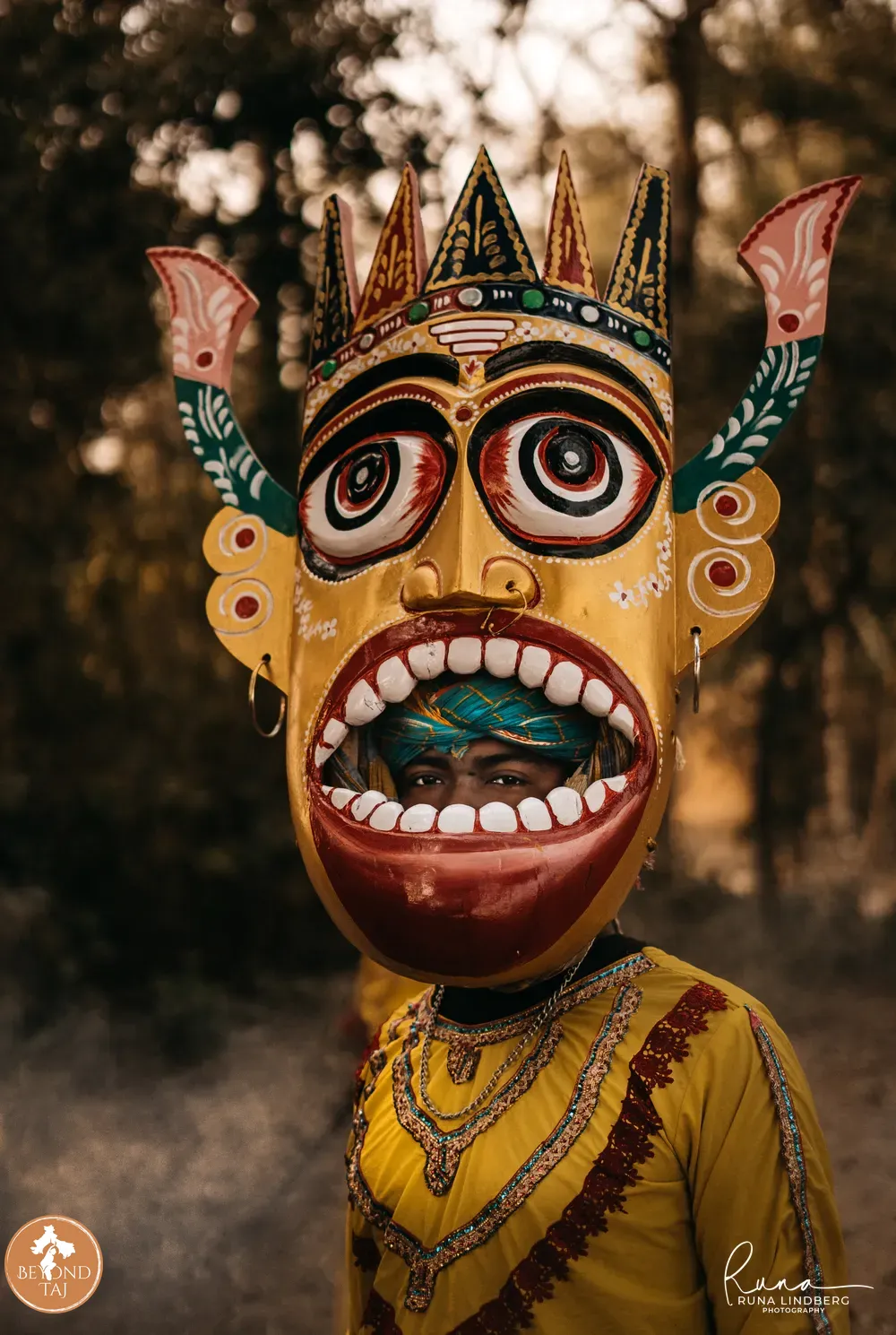 Young performer holding a golden horned Gomira mask beside his face