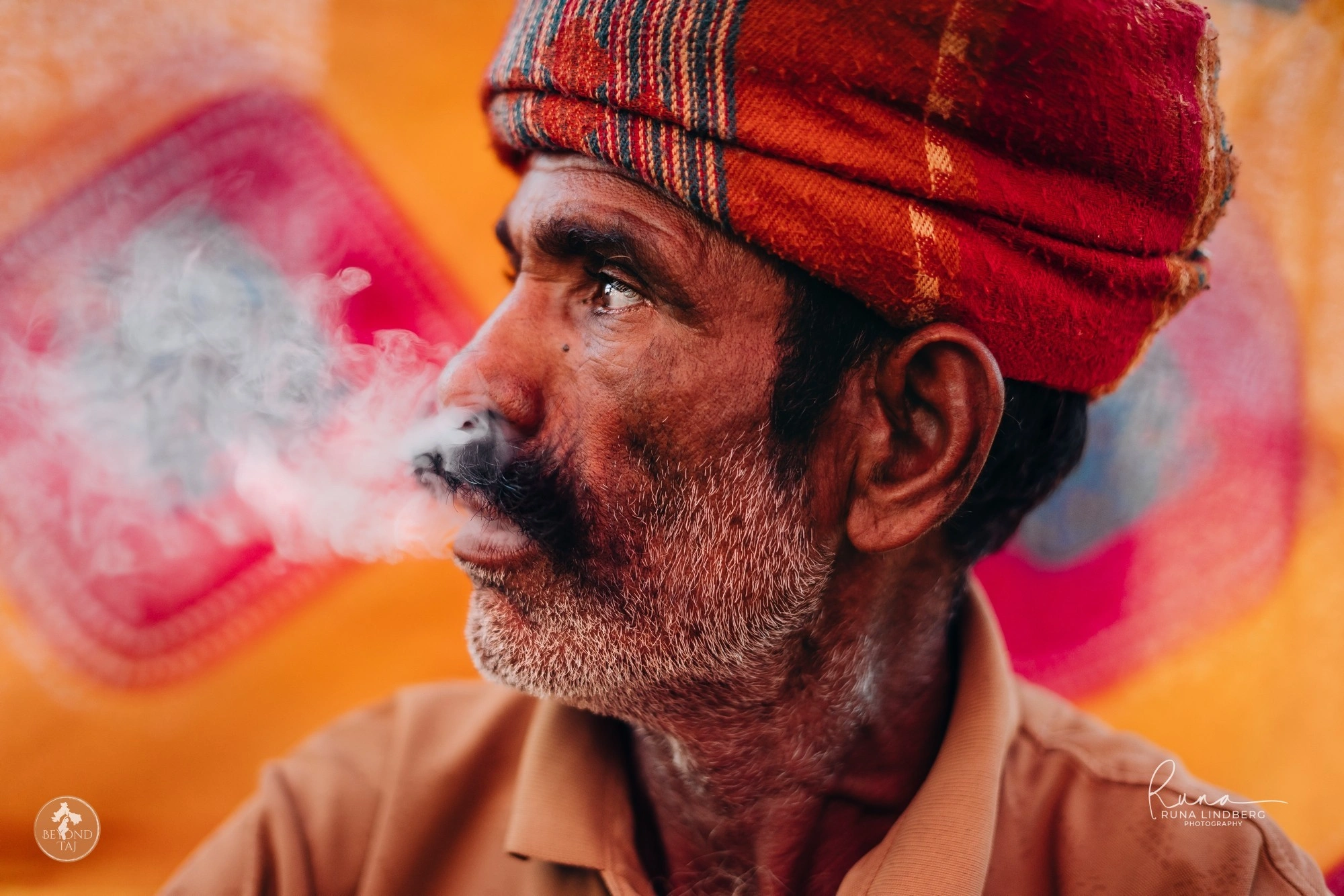 Rajasthani man in a red turban exhaling smoke at Pushkar Mela