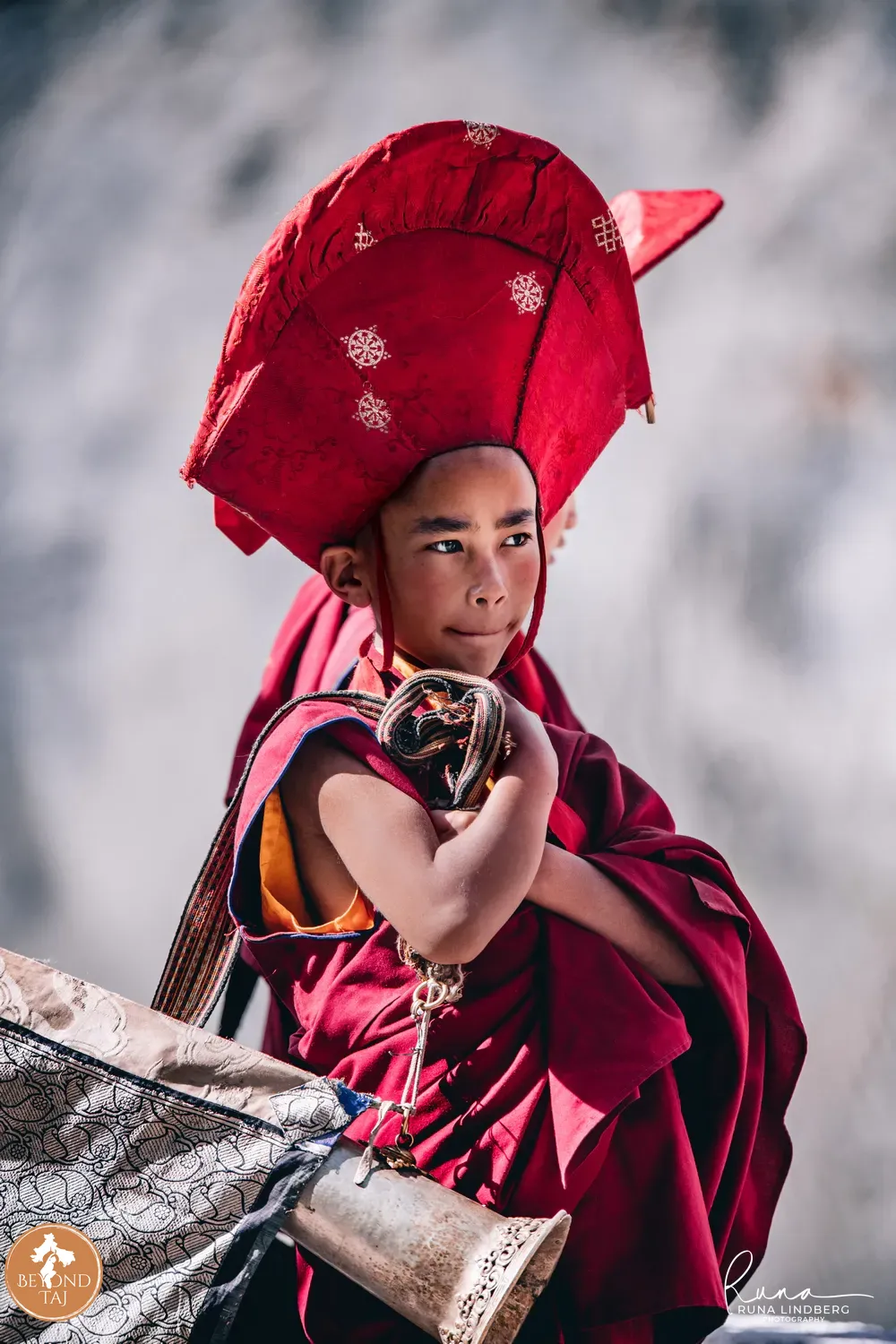 Young monk in ceremonial red headdress glancing at the camera