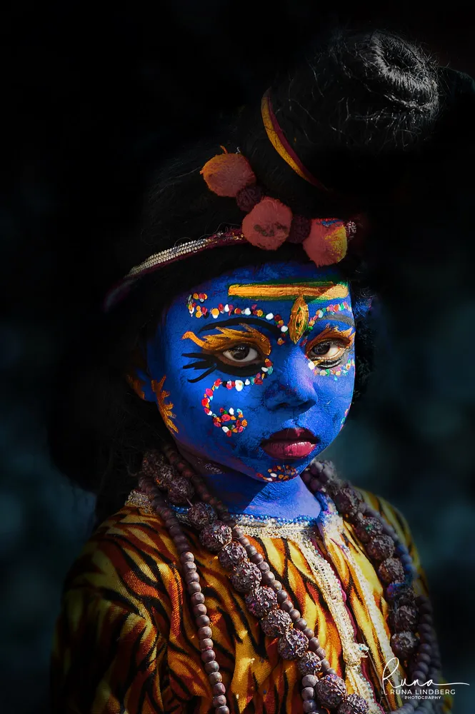 Child dressed as the god Shiva with blue face paint, a topknot, rudraksha beads and a tiger-print costume, Pushkar