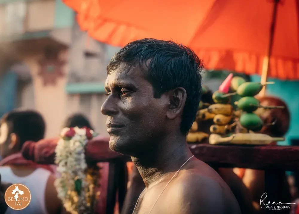 a profile portrait, face and shoulders, an orange umbrella and a fruits behind him